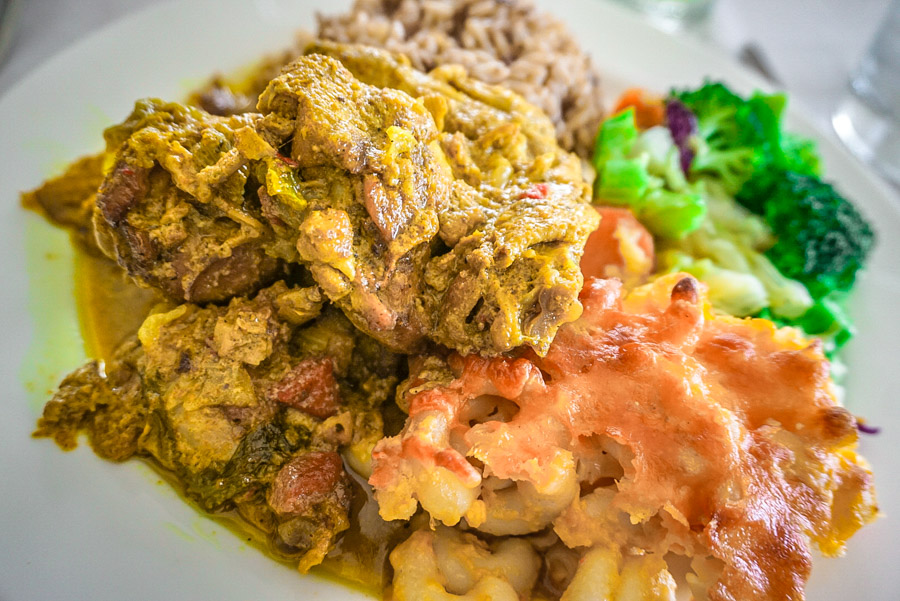Caribbean curried chicken served with rice, vegetables and a baked side dish