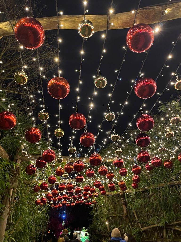A tunnel canopy of hanging red and gold baubles strung with cascading fairy lights