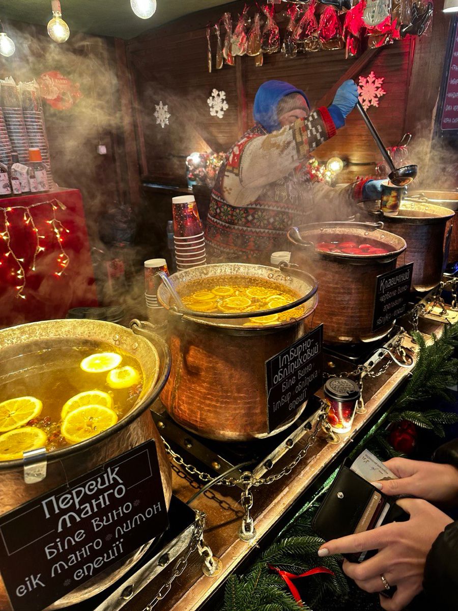 Steaming copper cauldrons of mulled wine with citrus slices at a festive drinks stall