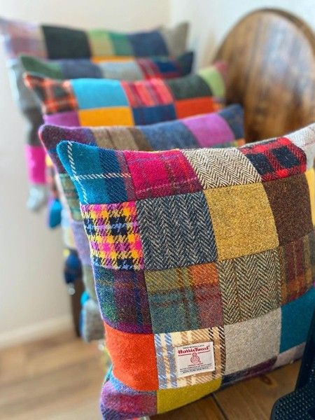 A row of colourful Harris Tweed patchwork cushions in tartan and herringbone squares