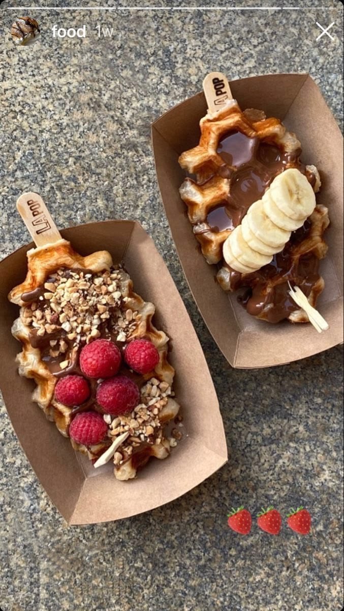 Belgian waffle pops in paper trays topped with melted chocolate, banana, raspberries and crushed nuts