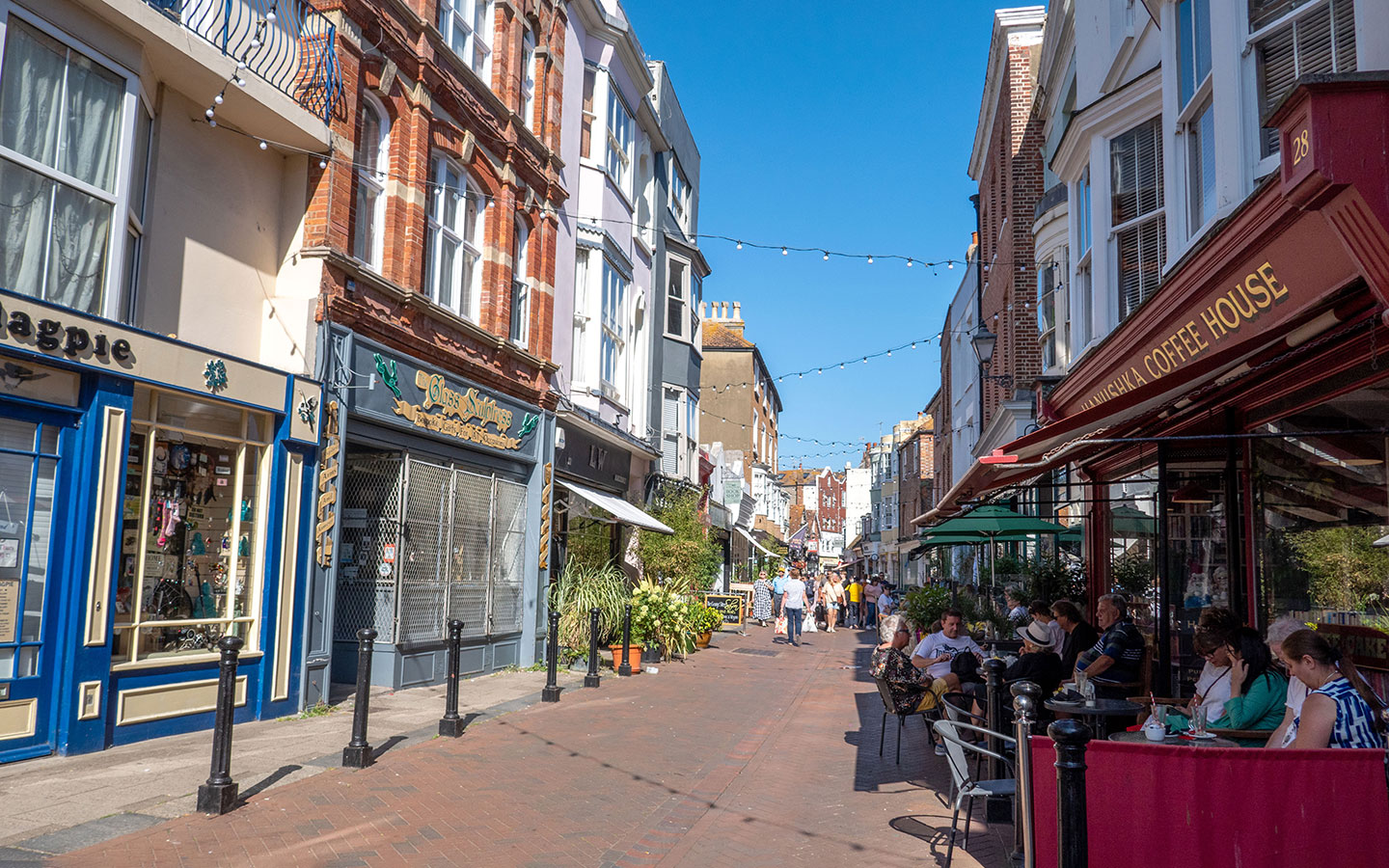 Shoppers and café-goers on a sunny Hastings high street lined with independent shops